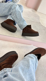 Bota Alaska Beyou Shoes marrom em camurça sintética com sola alta e forro interno de pelos, vista no espelho.
