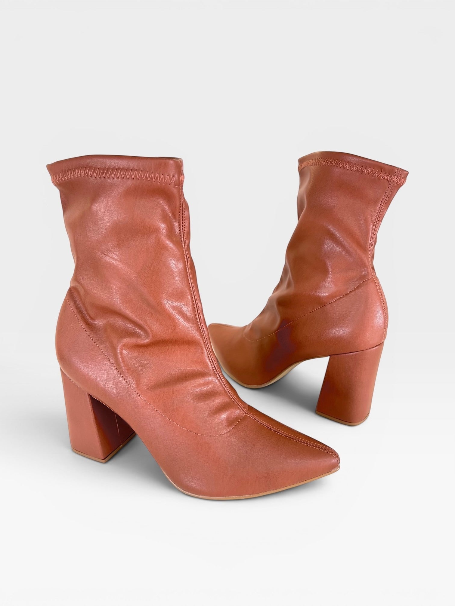 Bota Beyou Shoes Brooklyn na cor âmbar, feita em napa stretch com salto bloco de 9 cm e bico fino.