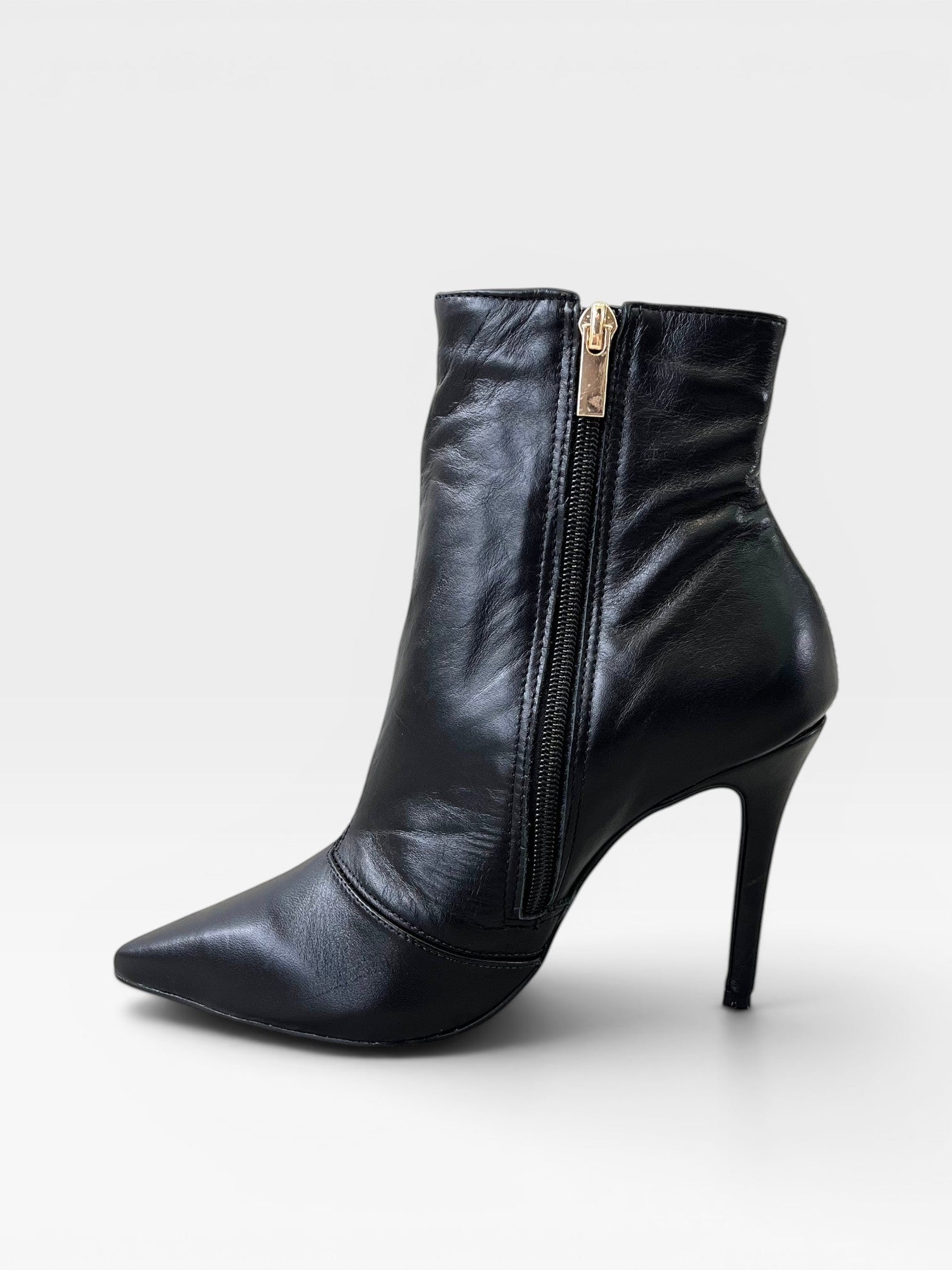 Bota Cannes Beyou Shoes preta em couro com salto fino de 9,5 cm, bico fino e fechamento lateral por zíper dourado.