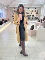 Mulher usando bota cano longo marrom Beyou Shoes com detalhe de fivela dourada em loja de calçados