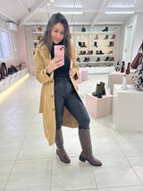 Mulher usando bota cano longo marrom Beyou Shoes com trench coat bege e calça preta em loja de calçados