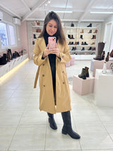 Mulher usando bota cano longo preta Beyou Shoes com sobretudo bege em loja de calçados