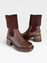 Bota Beyou Shoes Dublin marrom em napa com cano de tricô, salto médio e solado tratorado moderno.