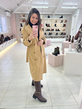 Mulher usando Bota Durazno marrom da Beyou Shoes com trench coat bege em loja de calçados.