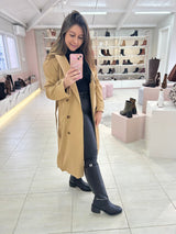 Mulher usando Bota Durazno preta de cano longo Beyou Shoes com trench coat bege em loja de calçados