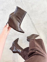 Bota Beyou Shoes Manchester marrom em couro com salto anabela, exibida na mão e calçada com calça marrom.