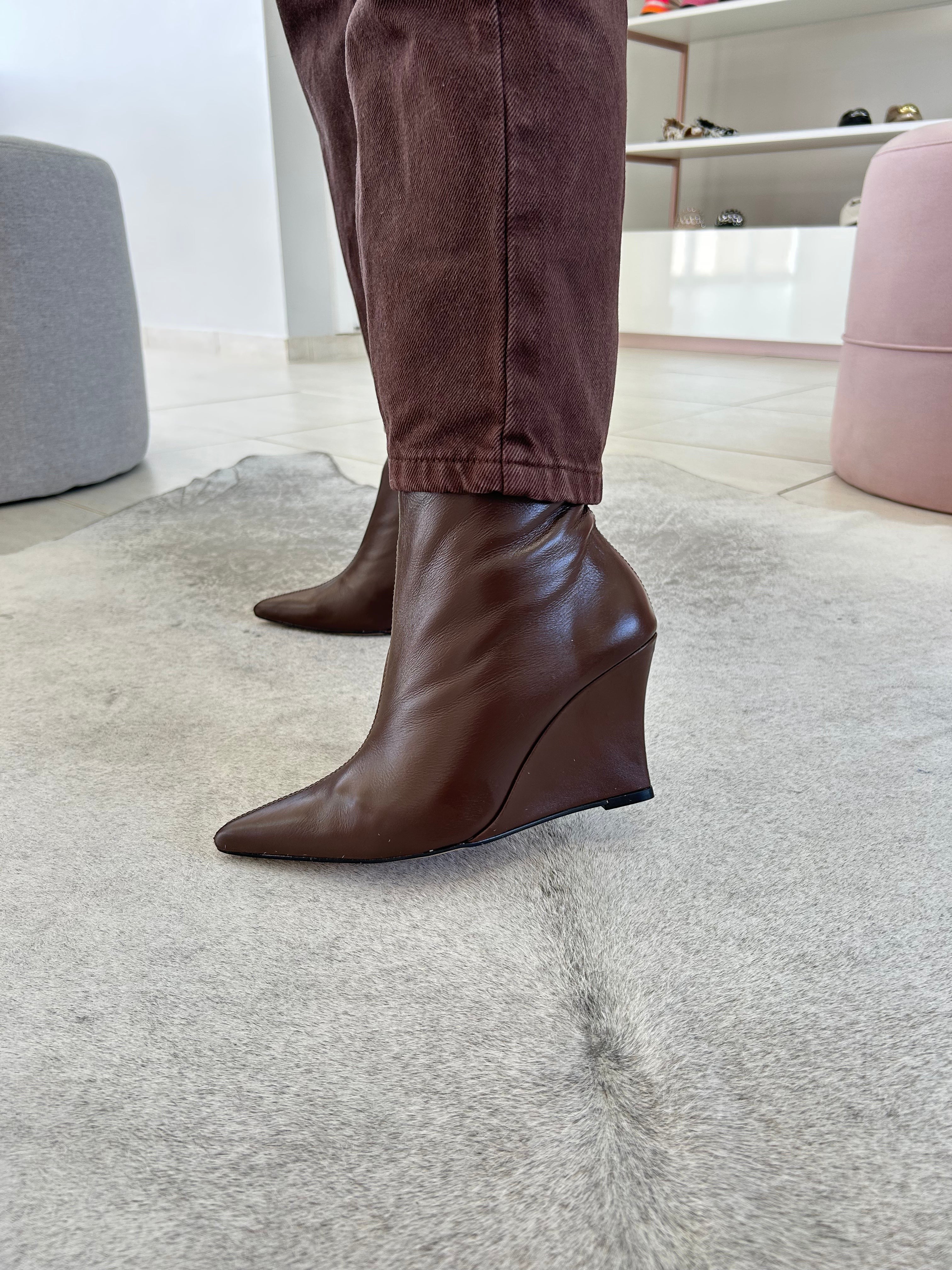 Bota Manchester Beyou Shoes em couro marrom com salto anabela e bico fino, vista lateral em ambiente interno.