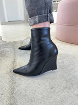 Bota Manchester Beyou Shoes preta em couro com salto anabela e bico fino, usada com calça jeans cinza.