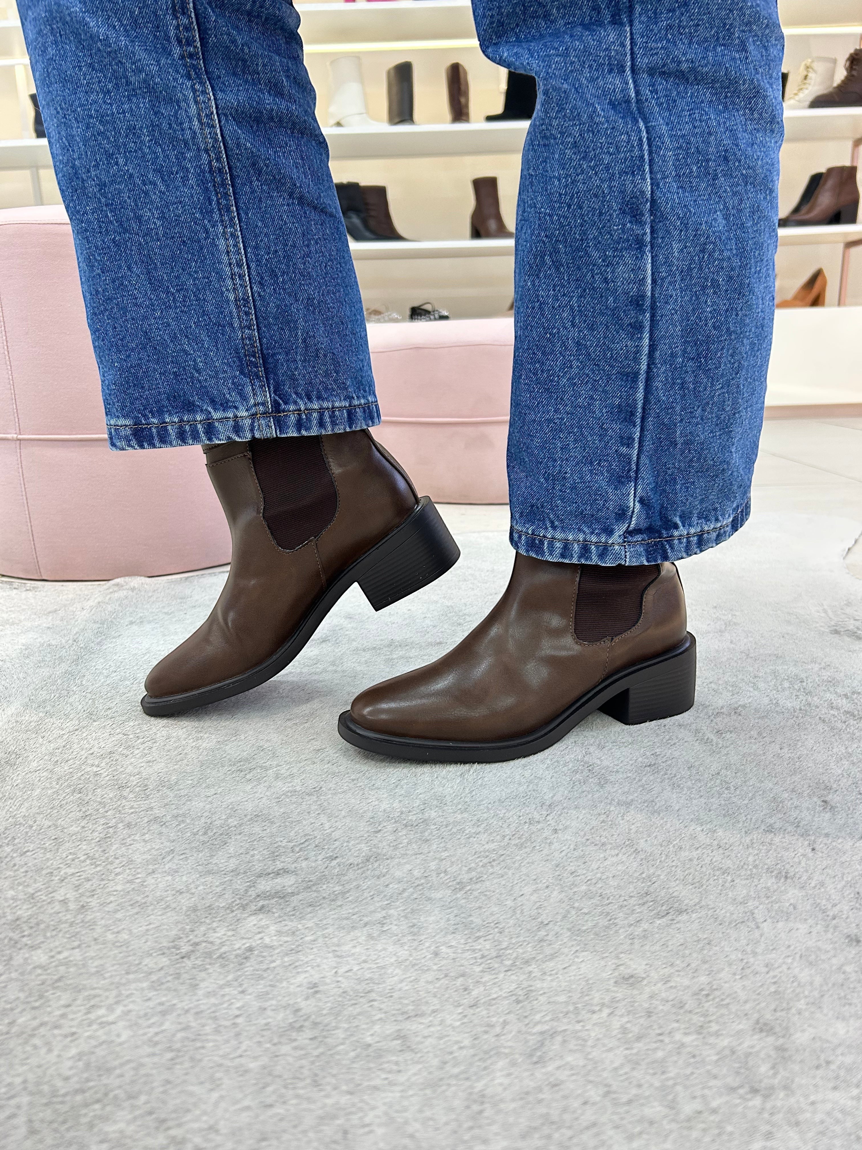 Bota Beyou Shoes Ohio marrom em napa destroyed com elástico lateral, usada com calça jeans em ambiente de loja.