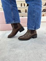 Bota Beyou Shoes Ohio marrom em napa destroyed com elástico lateral, usada com calça jeans em ambiente de loja.