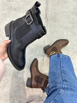 Bota Beyou Shoes Ohio preta em napa destroyed com fivela lateral e elástico, exibida em mão e no pé com calça jeans