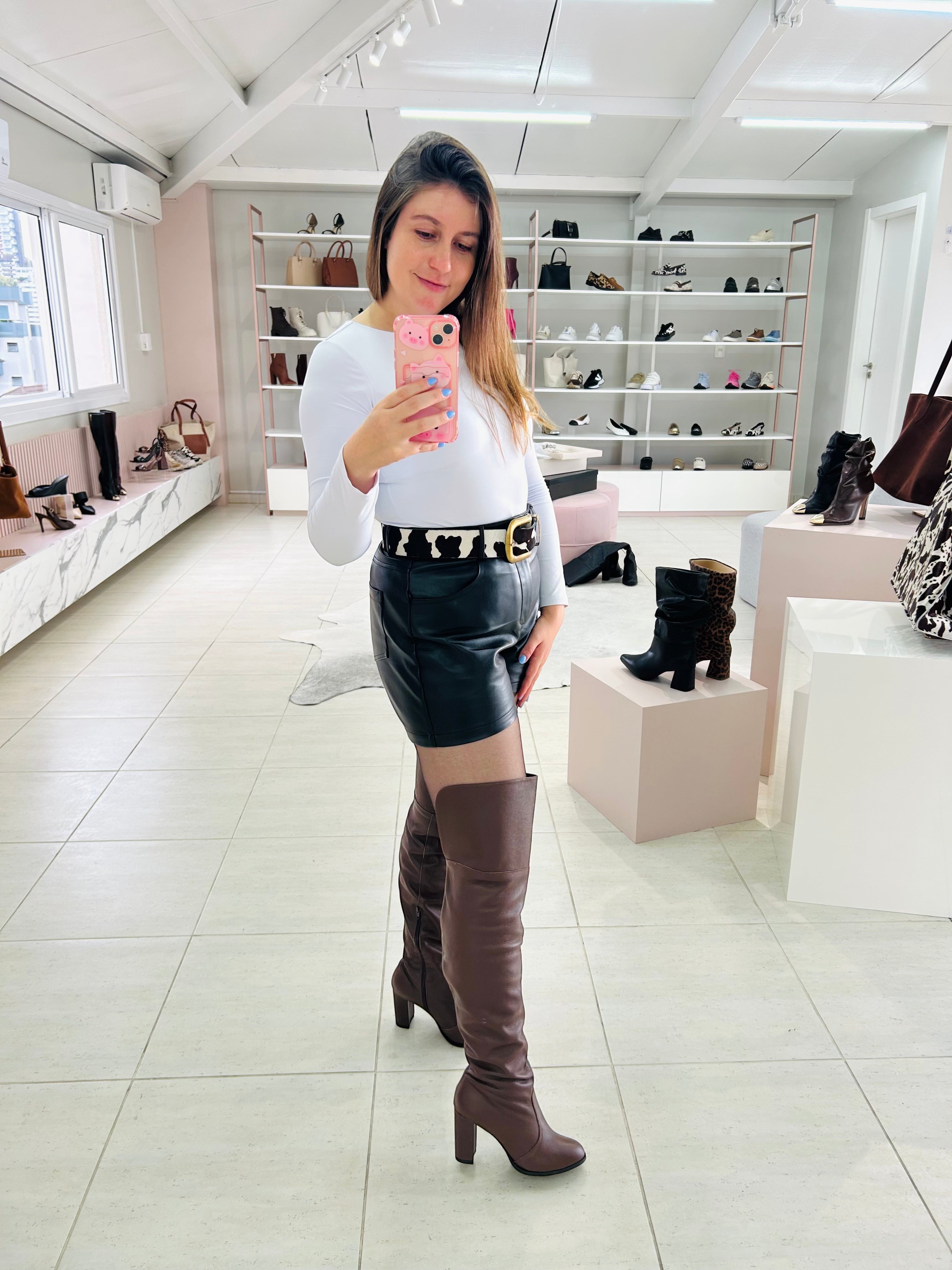 Mulher usando bota over the knee marrom de couro Beyou Shoes com salto alto em loja de calçados