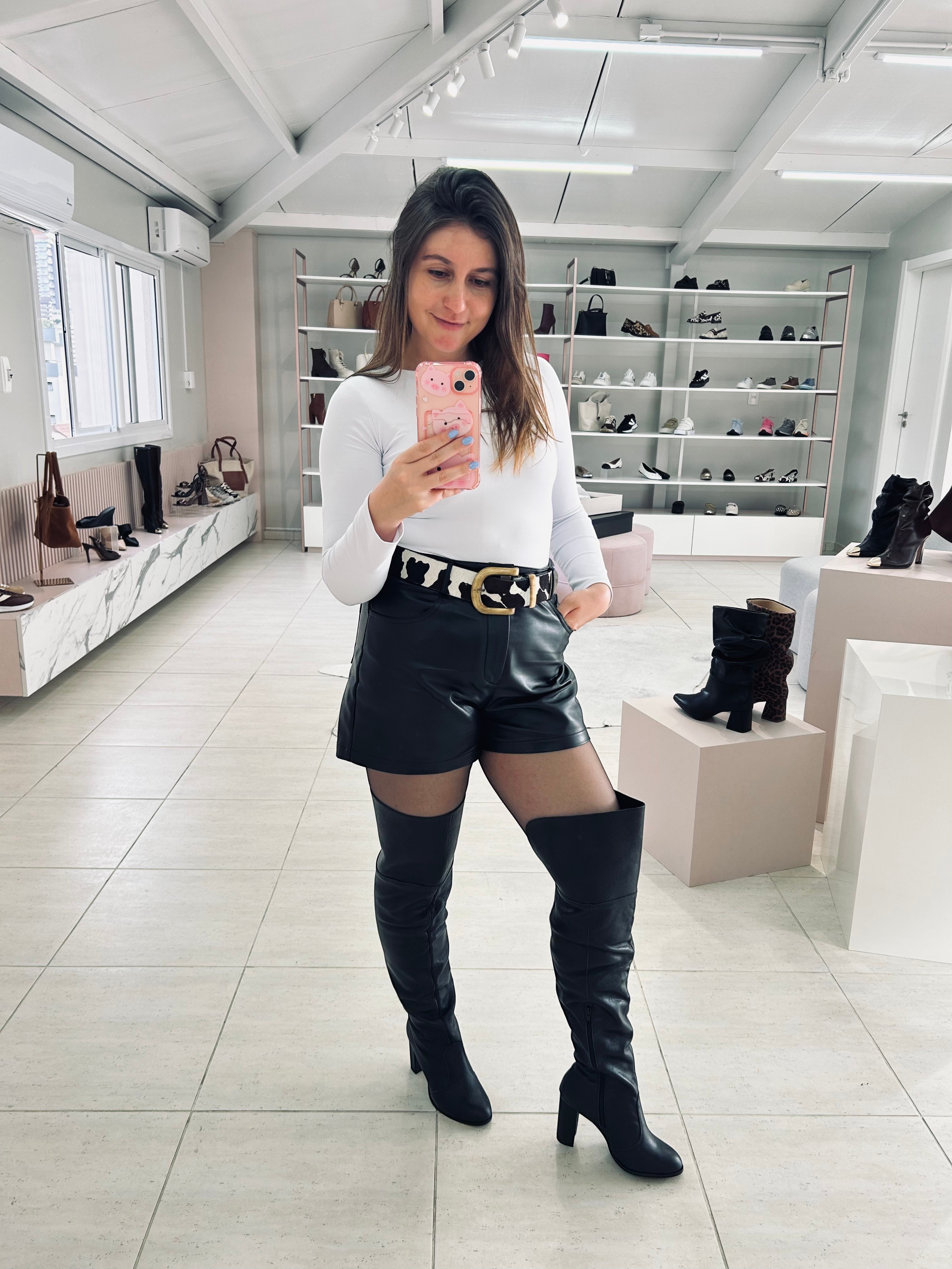 Mulher usando bota over the knee preta de couro Beyou Shoes com salto de 9 cm em ambiente de loja