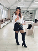 Mulher usando bota over the knee preta de couro Beyou Shoes com salto de 9 cm em ambiente de loja