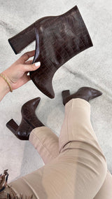 Bota Paris Beyou Shoes marrom em couro com textura croco, salto alto de 9 cm e fechamento lateral por zíper.