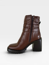 Bota Beyou Shoes Trento marrom em couro com salto bloco de 9,5 cm, zíper lateral e tiras decorativas no tornozelo.