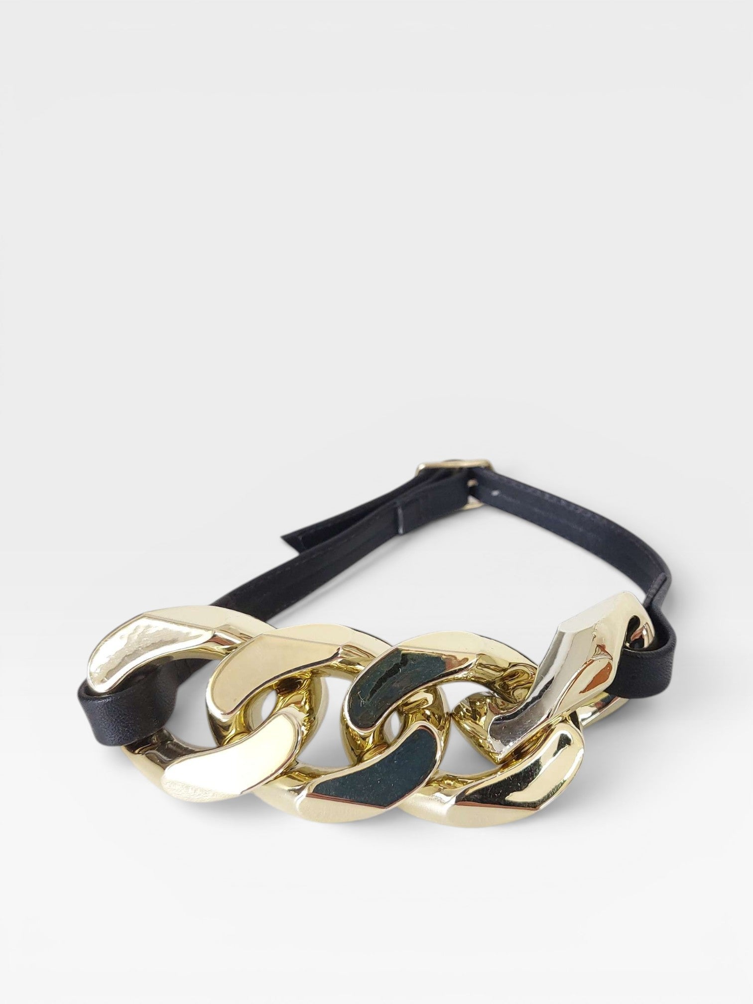 Acessório Beyou Shoes composto por corrente dourada de elos grandes entrelaçada em uma cinta preta ajustável.
