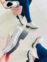 Mocassim Beyou Shoes Punta del Leste prata em napa com solado tratorado preto, visto em mãos e nos pés com calça jeans.