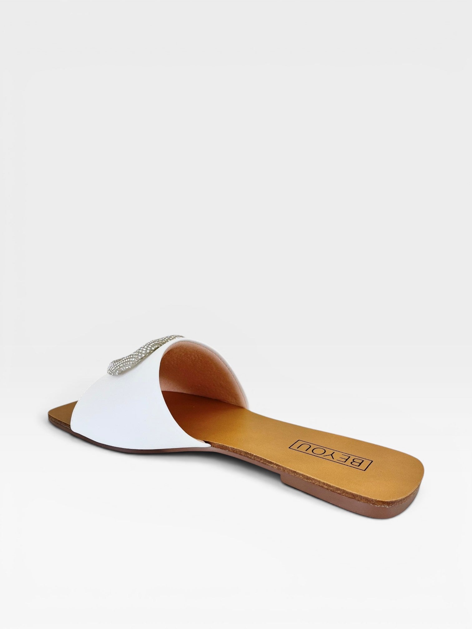 Rasteira Búzios branca Beyou Shoes em napa com detalhe de coração em brilho sobre fundo neutro