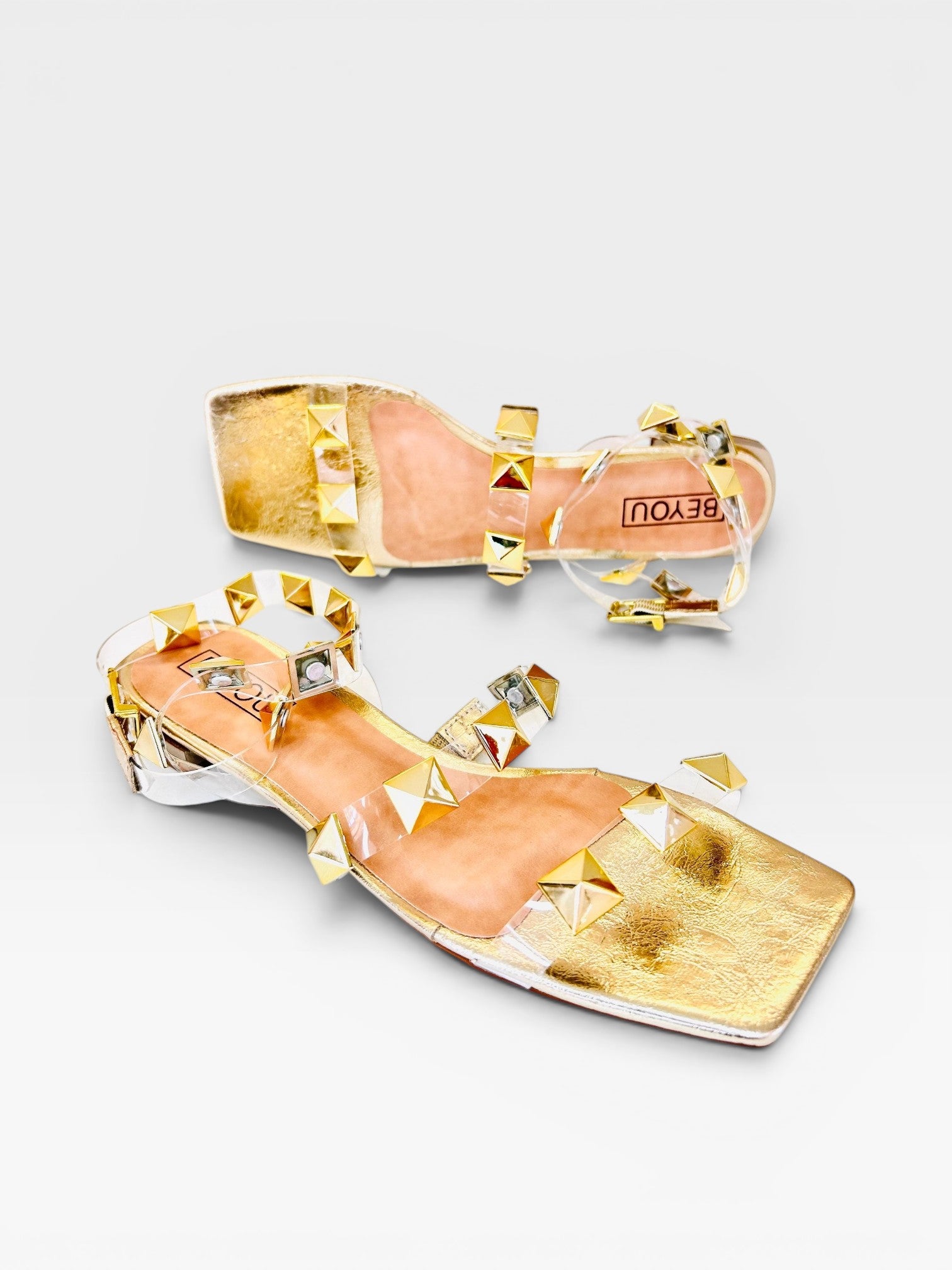 Rasteira Beyou Shoes Las Vegas ouro light com tiras de vinil transparente e aplicações de tachas douradas