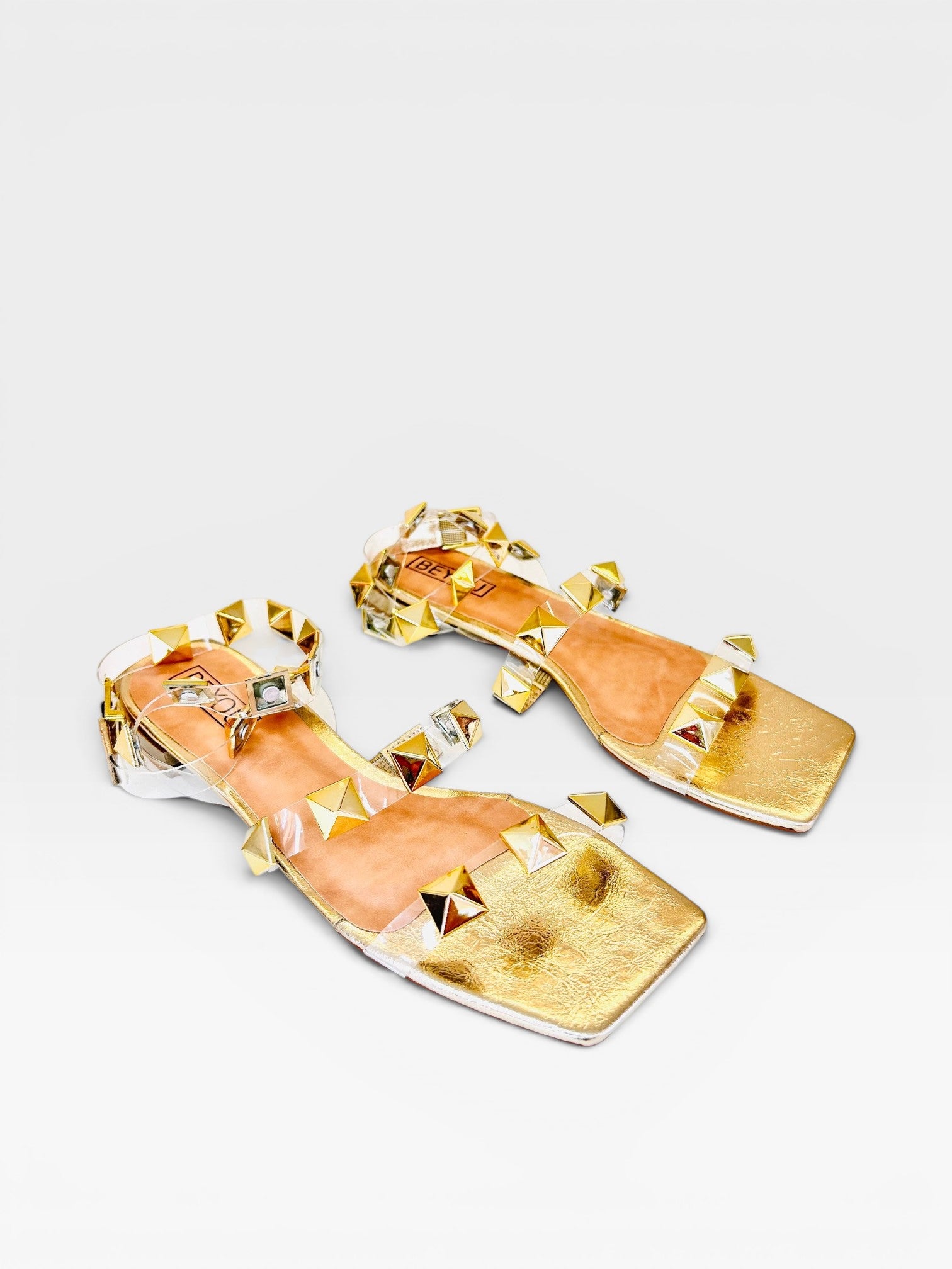 Rasteira Beyou Shoes Las Vegas ouro light com tiras de vinil transparente e aplicações de tachas douradas