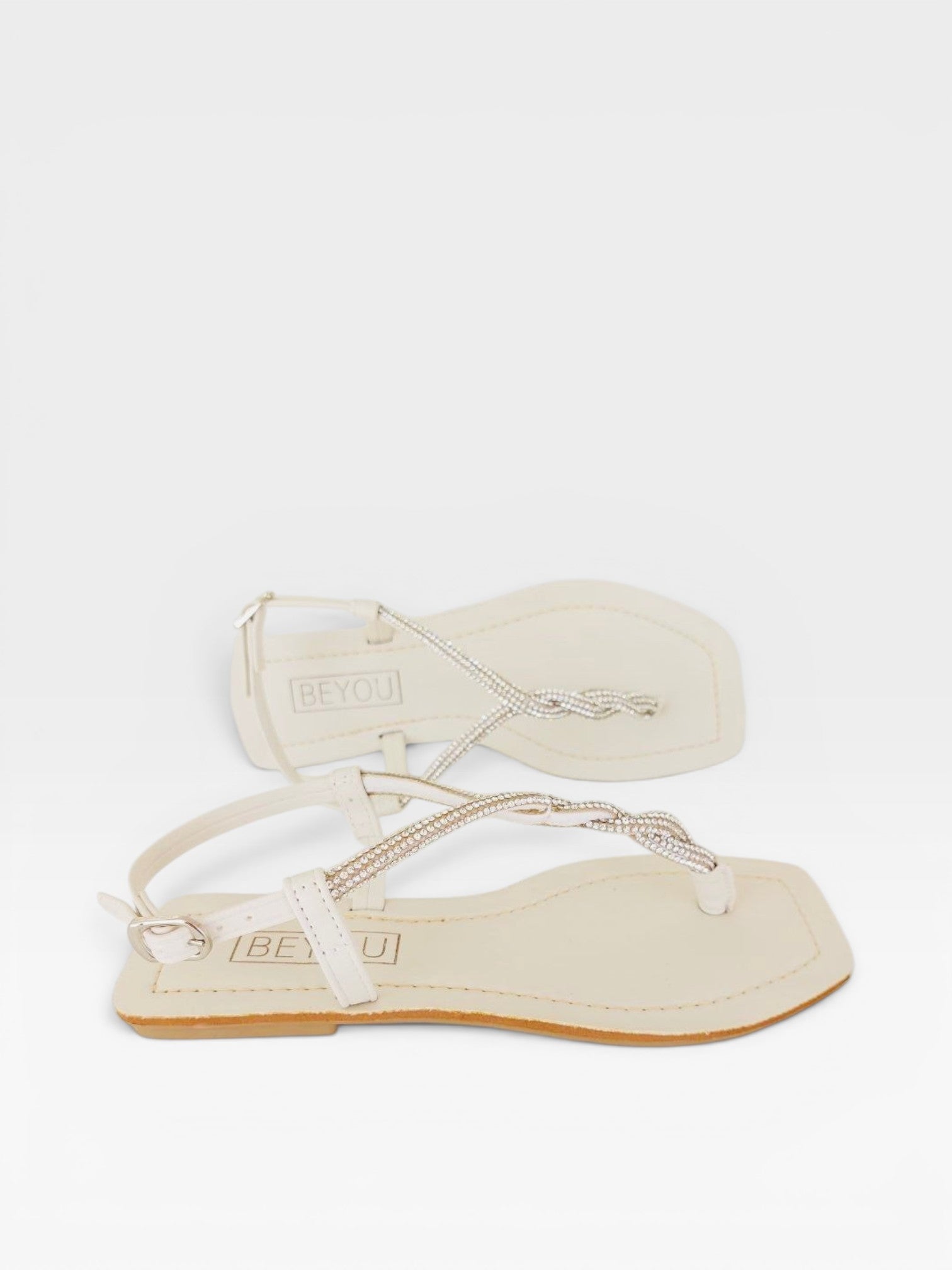 Rasteira Beyou Shoes Noronha off white em napa com tiras finas trançadas e detalhes em pedrarias brilhantes