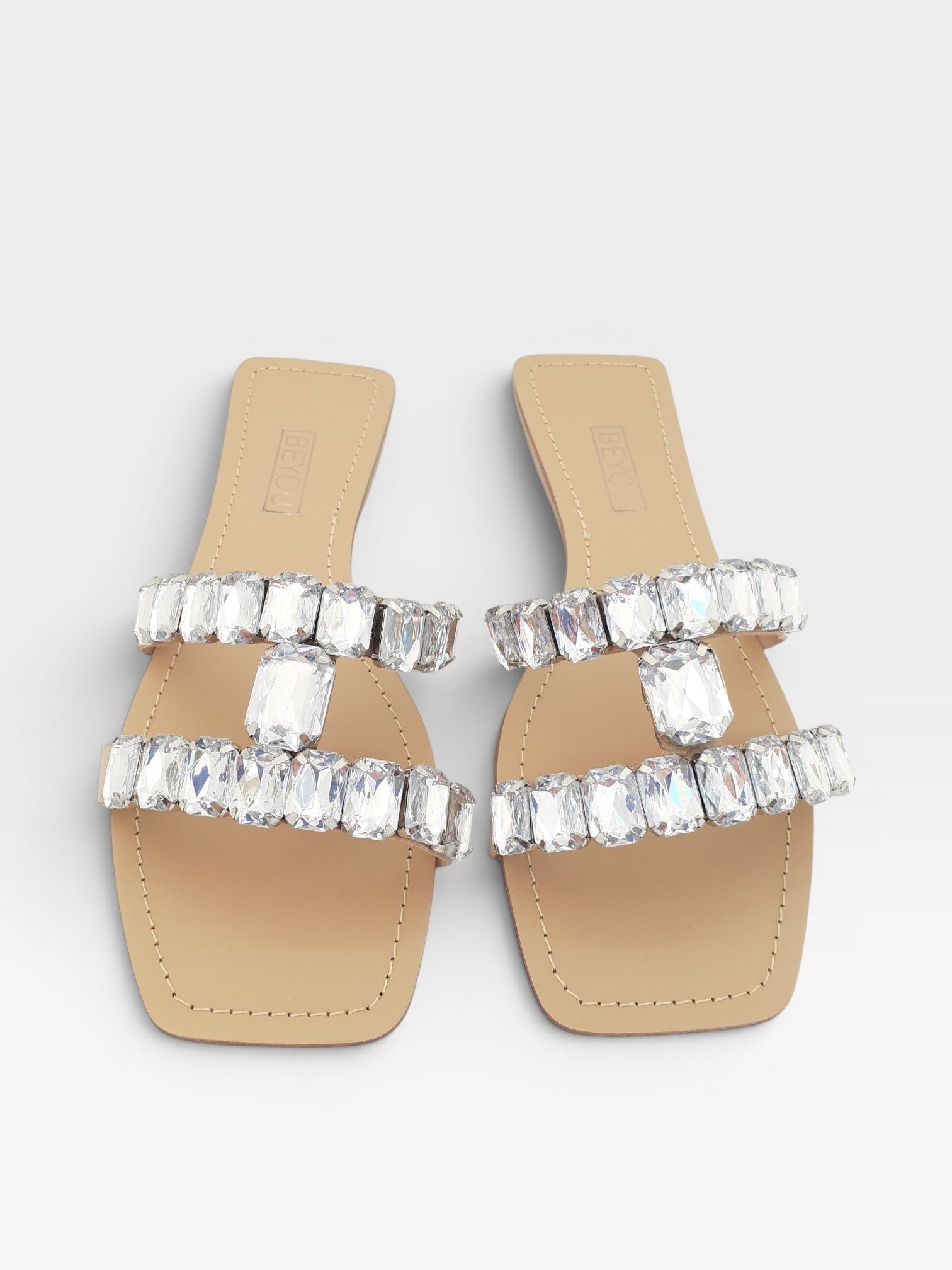 Rasteira Beyou Shoes nude em napa com tiras adornadas por pedrarias brilhantes e bico quadrado