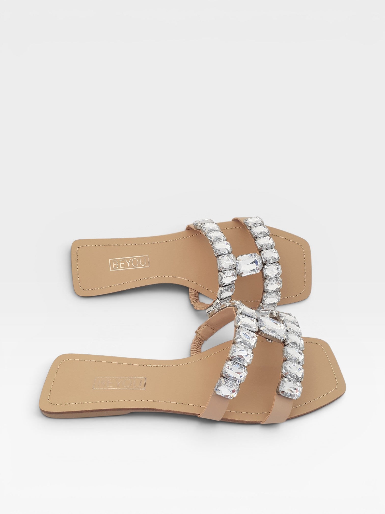 Rasteira Beyou Shoes Maragogi nude em napa com tiras adornadas por pedrarias brilhantes e bico quadrado