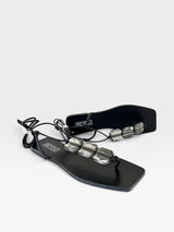 Rasteira preta Beyou Shoes com tiras de amarração e detalhes em pedrarias transparentes sobre fundo branco.