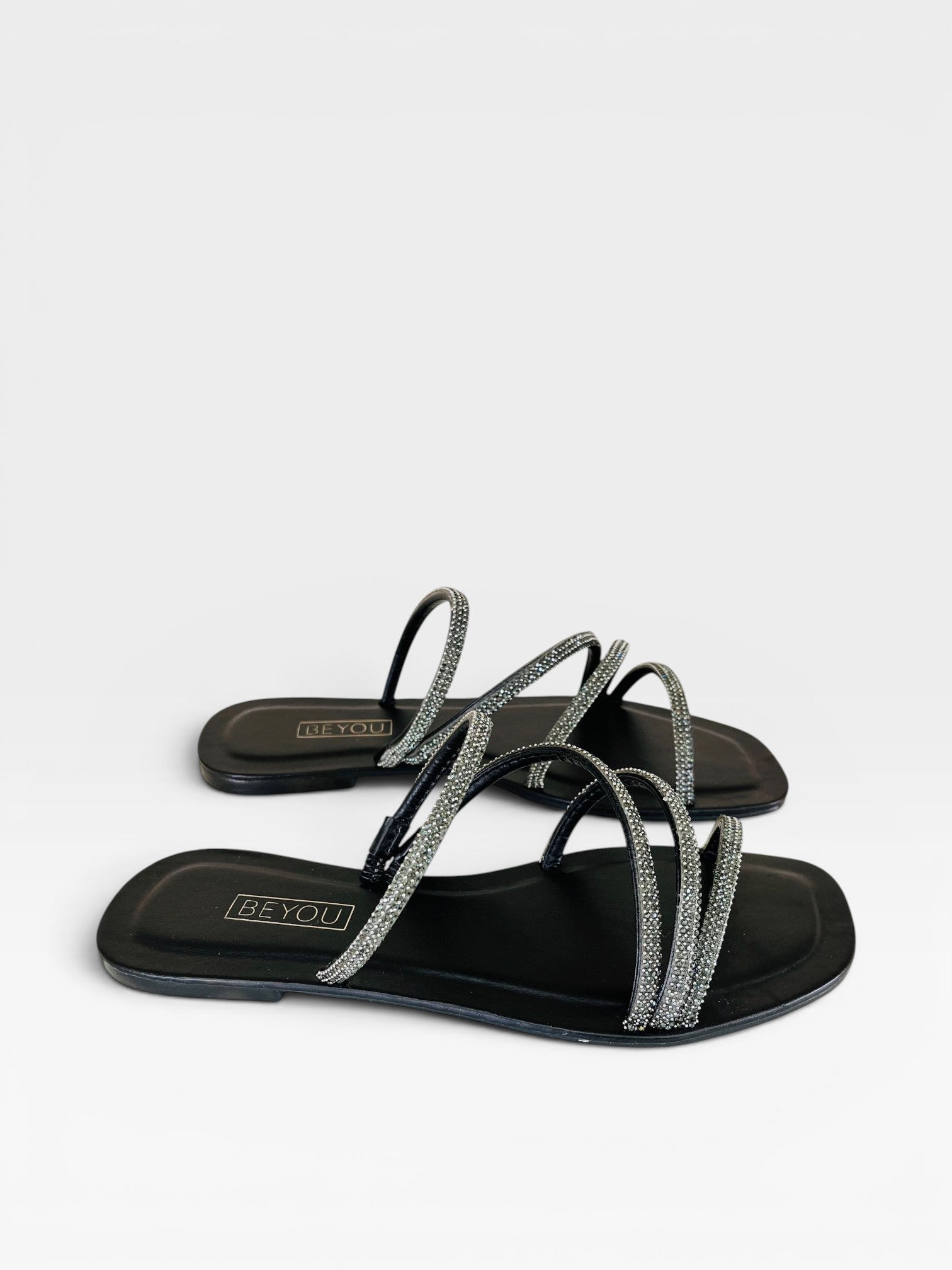 Rasteira Beyou Shoes preta em napa com tiras finas adornadas por pedrarias brilhantes e design elegante