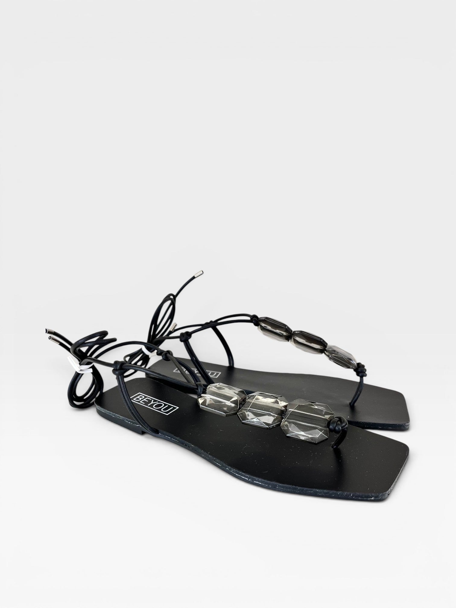 Rasteira preta Beyou Shoes com pedrarias transparentes e amarração no tornozelo em material napa