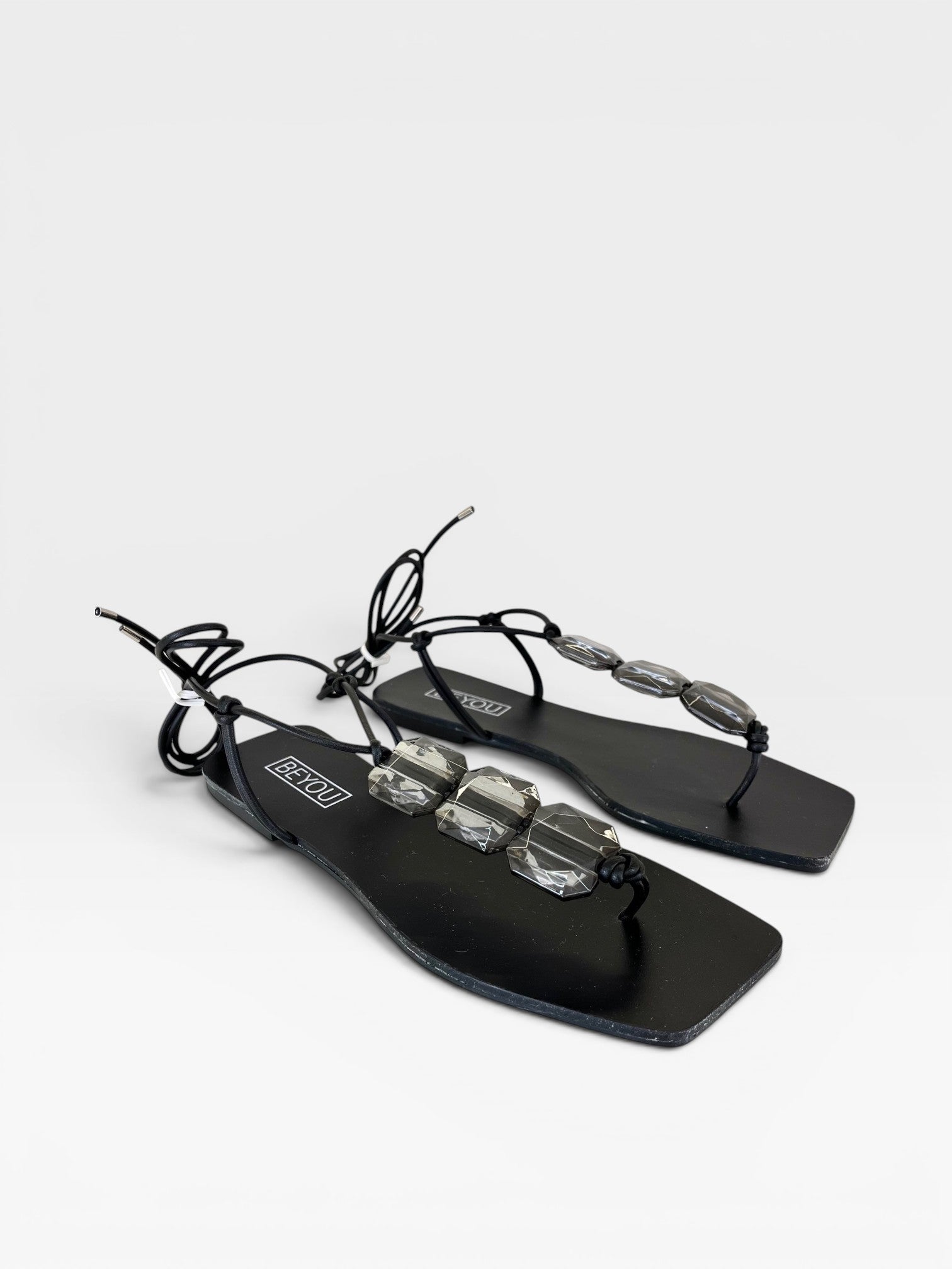 Rasteira preta Beyou Shoes com pedrarias transparentes e amarração no tornozelo em material napa