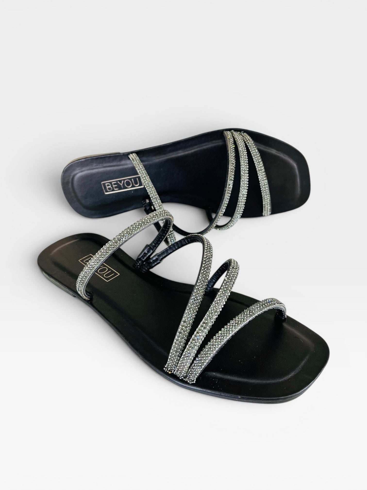 Rasteira Beyou Shoes preta em napa com tiras finas adornadas por pedrarias brilhantes e bico quadrado