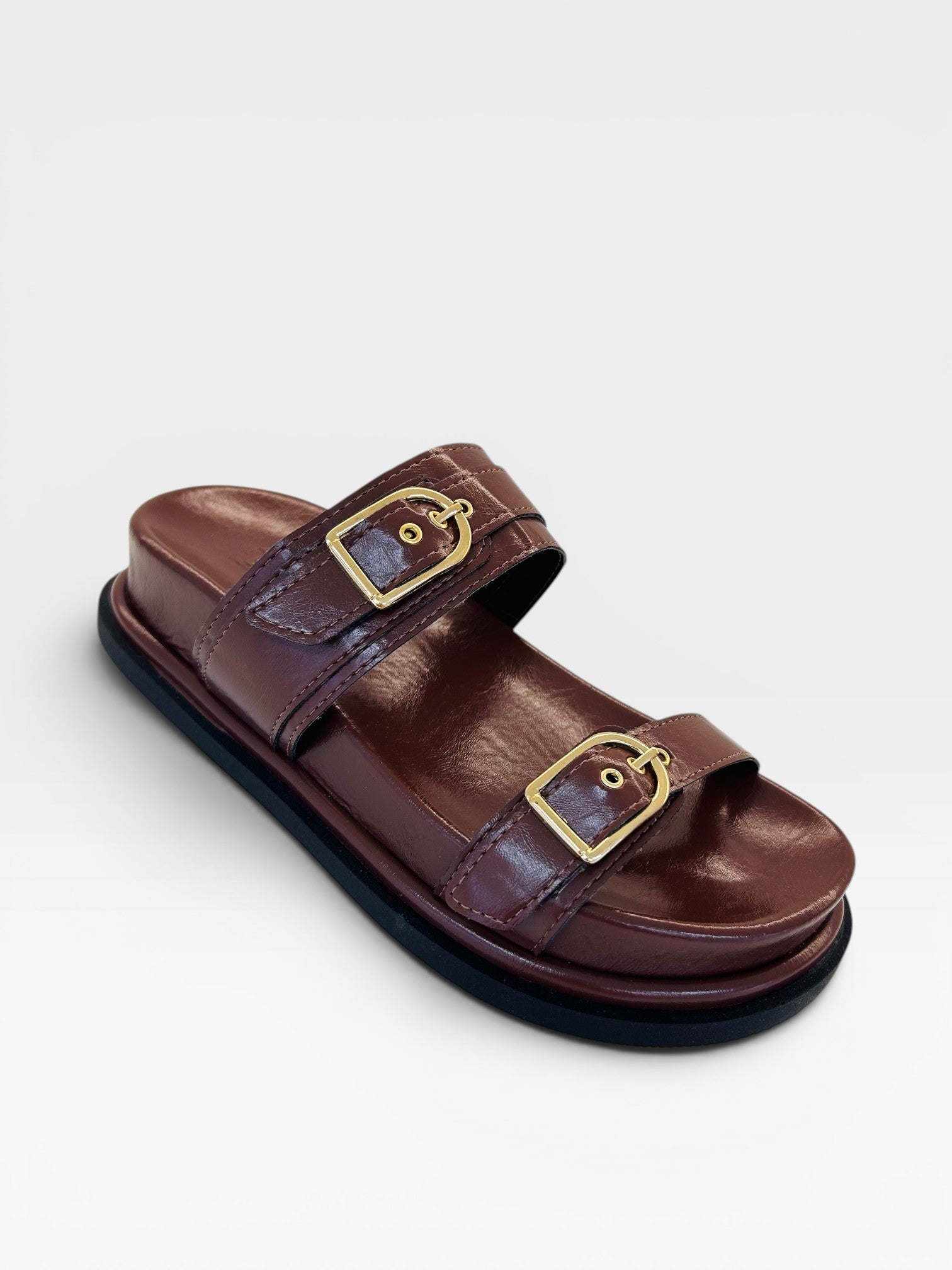 Sandália Birken Coimbra Beyou Shoes marrom em napa com duas tiras e fivelas douradas, solado baixo de 2 cm.