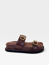 Sandália Birken Coimbra Beyou Shoes marrom em napa com duas tiras e fivelas douradas, solado plano de 2 cm.
