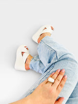Sandália flatform branca Beyou Shoes com tiras em X, calçada em pés com calça jeans clara e anel de pedra