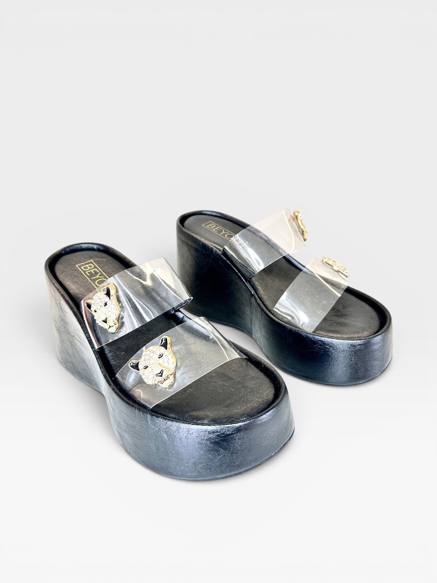 Sandália flatform preta Beyou Shoes em napa e vinil com tiras transparentes e detalhes de felinos dourados.