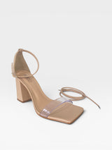 Sandália Beyou Shoes Marbella nude em napa com salto bloco, tira transparente e amarração no tornozelo.