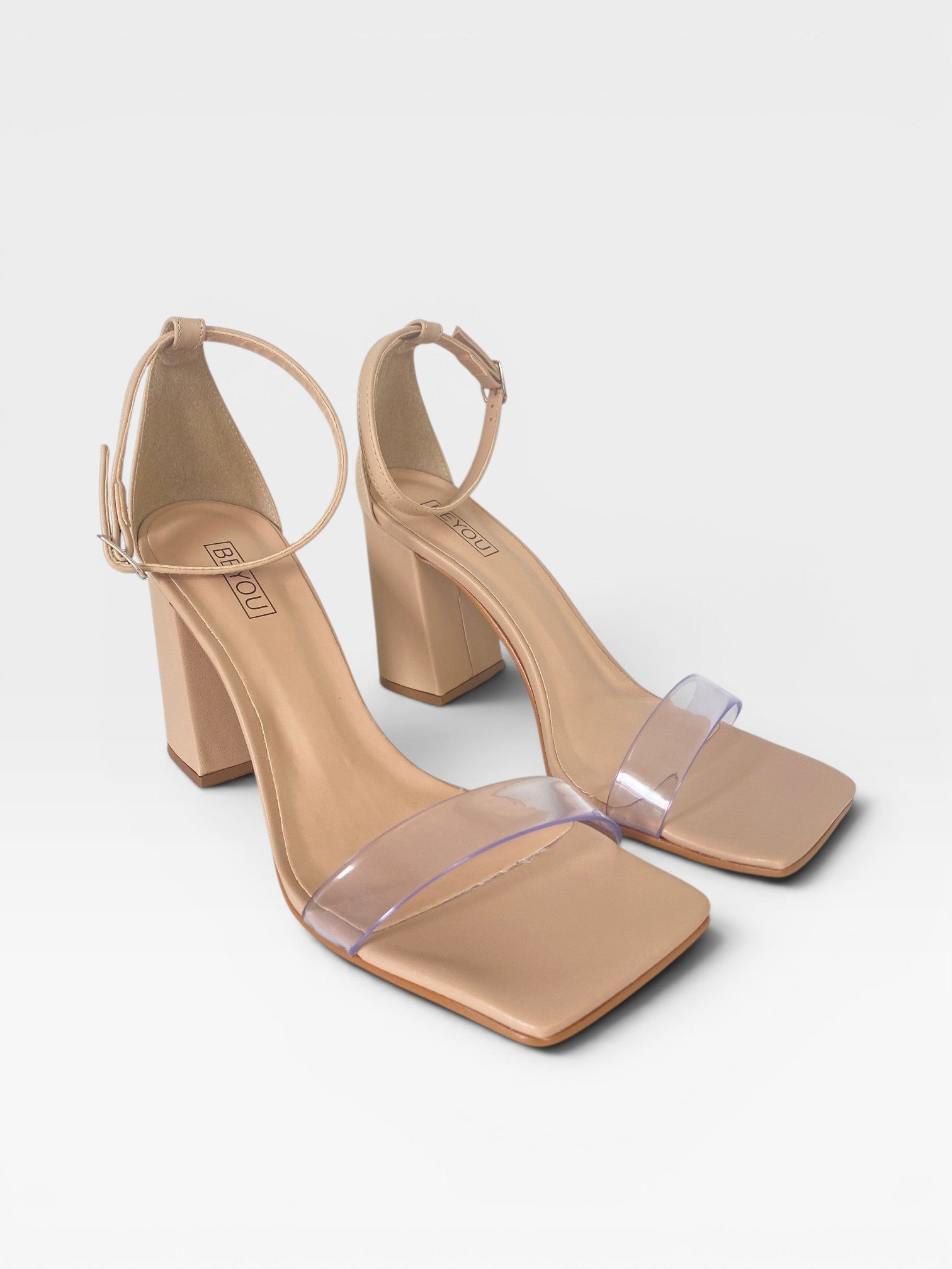 Sandália Beyou Shoes Marbella nude com salto bloco, tira frontal transparente e fechamento por fivela no tornozelo.
