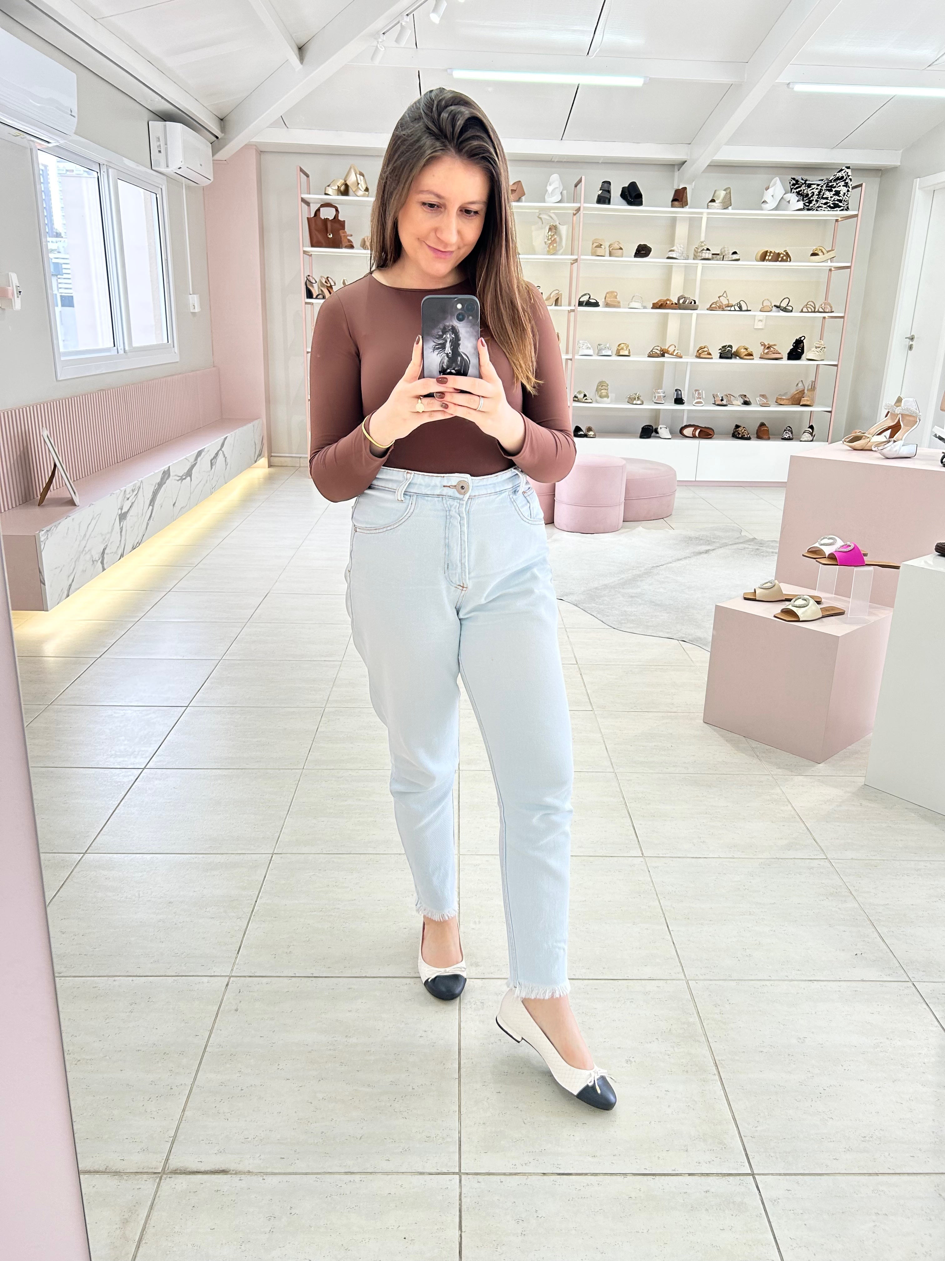 Mulher usando sapatilha Beyou Shoes Bari off-white com biqueira preta em napa, combinada com jeans claro e blusa marrom.