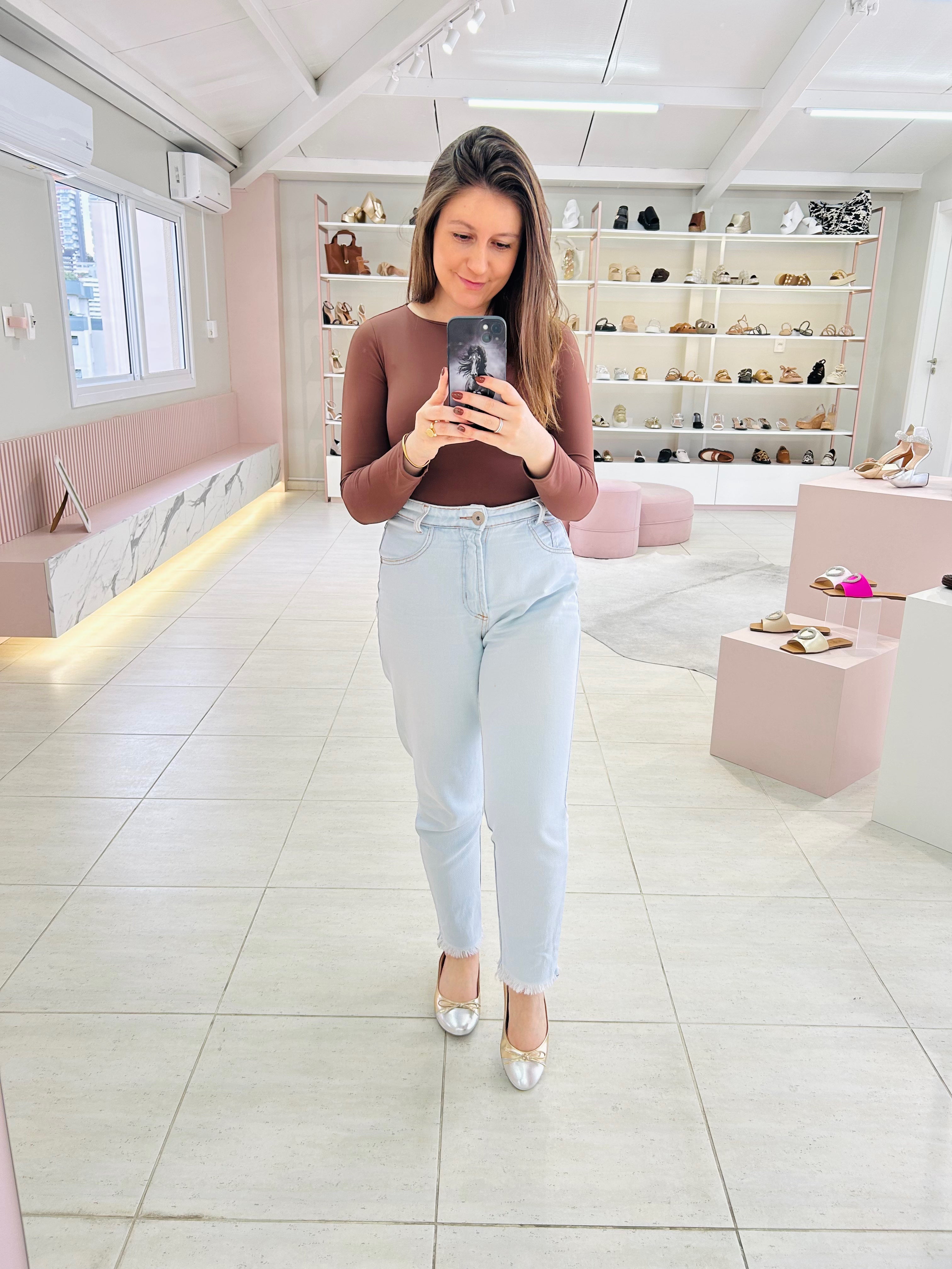 Mulher usando sapatilha Beyou Shoes Bari em napa ouro light e prata com laço delicado em ambiente de loja.