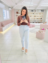 Mulher usando sapatilha Beyou Shoes Bari em napa ouro light e prata com laço delicado em ambiente de loja.
