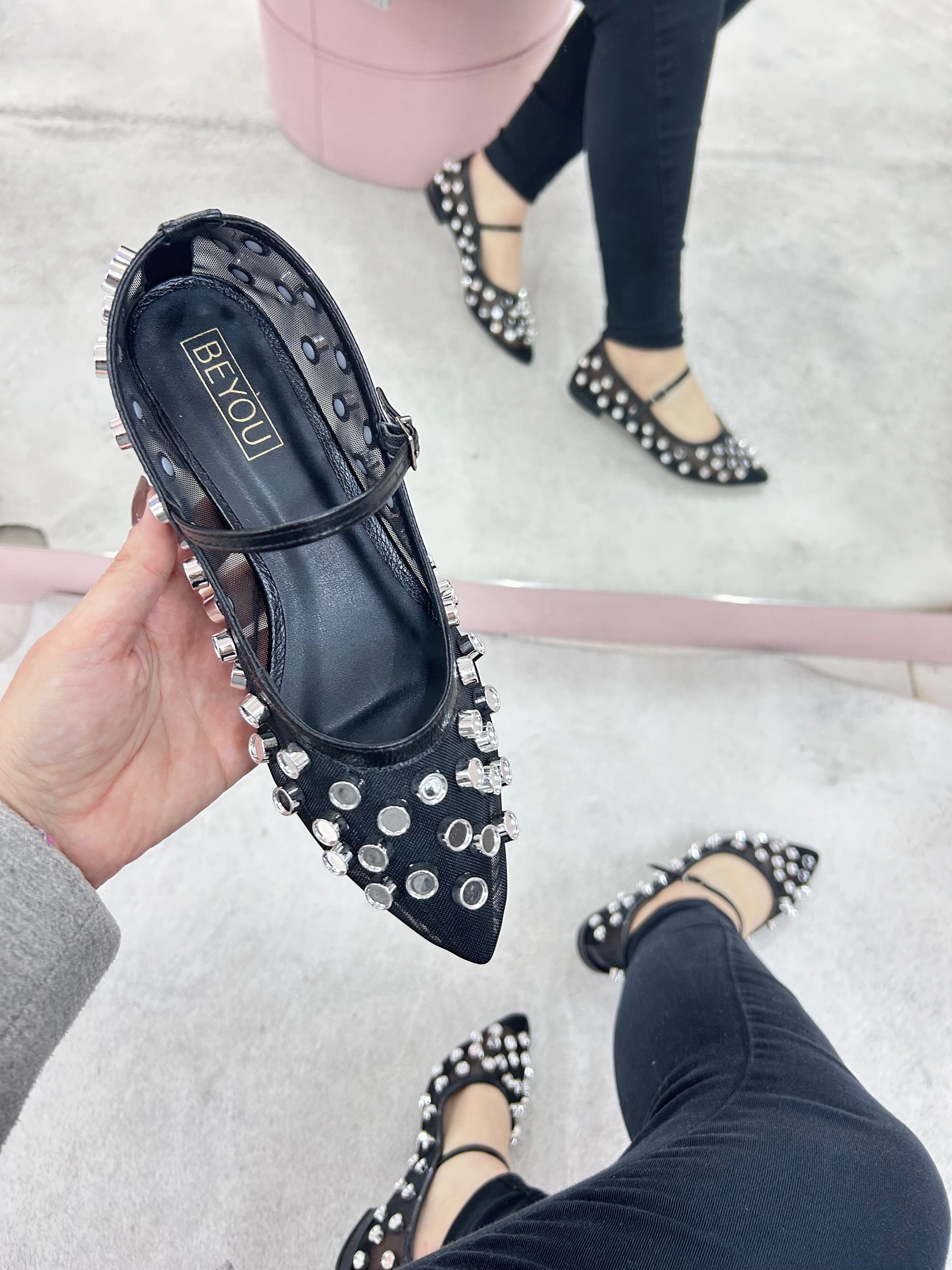 Sapatilha Doha Beyou Shoes preta em tela com brilhos e tira no peito do pé, vista em mão e refletida no espelho