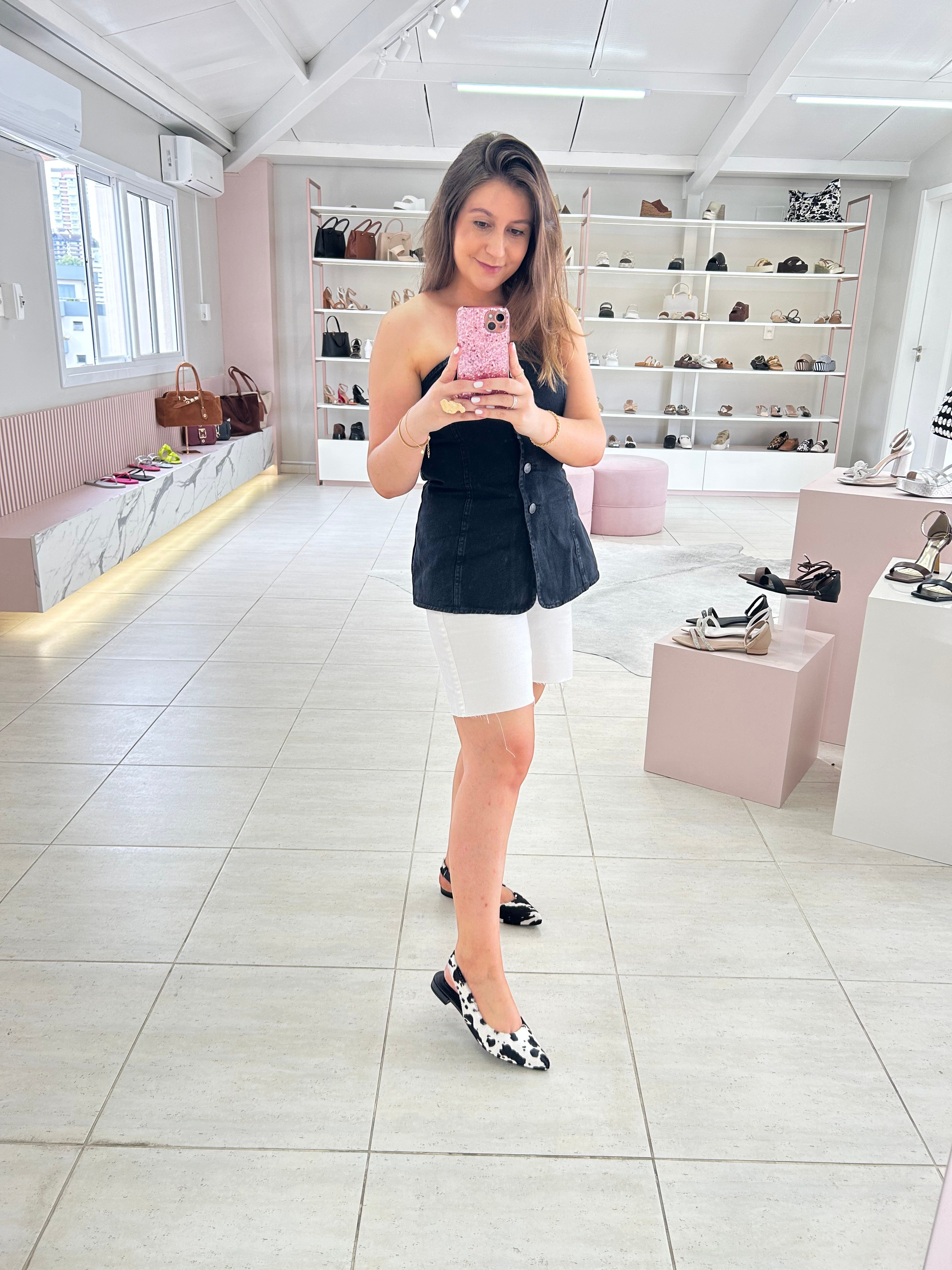 Mulher usando slingback Beyou Shoes de couro com estampa animal print de vaquinha preta e branca em loja