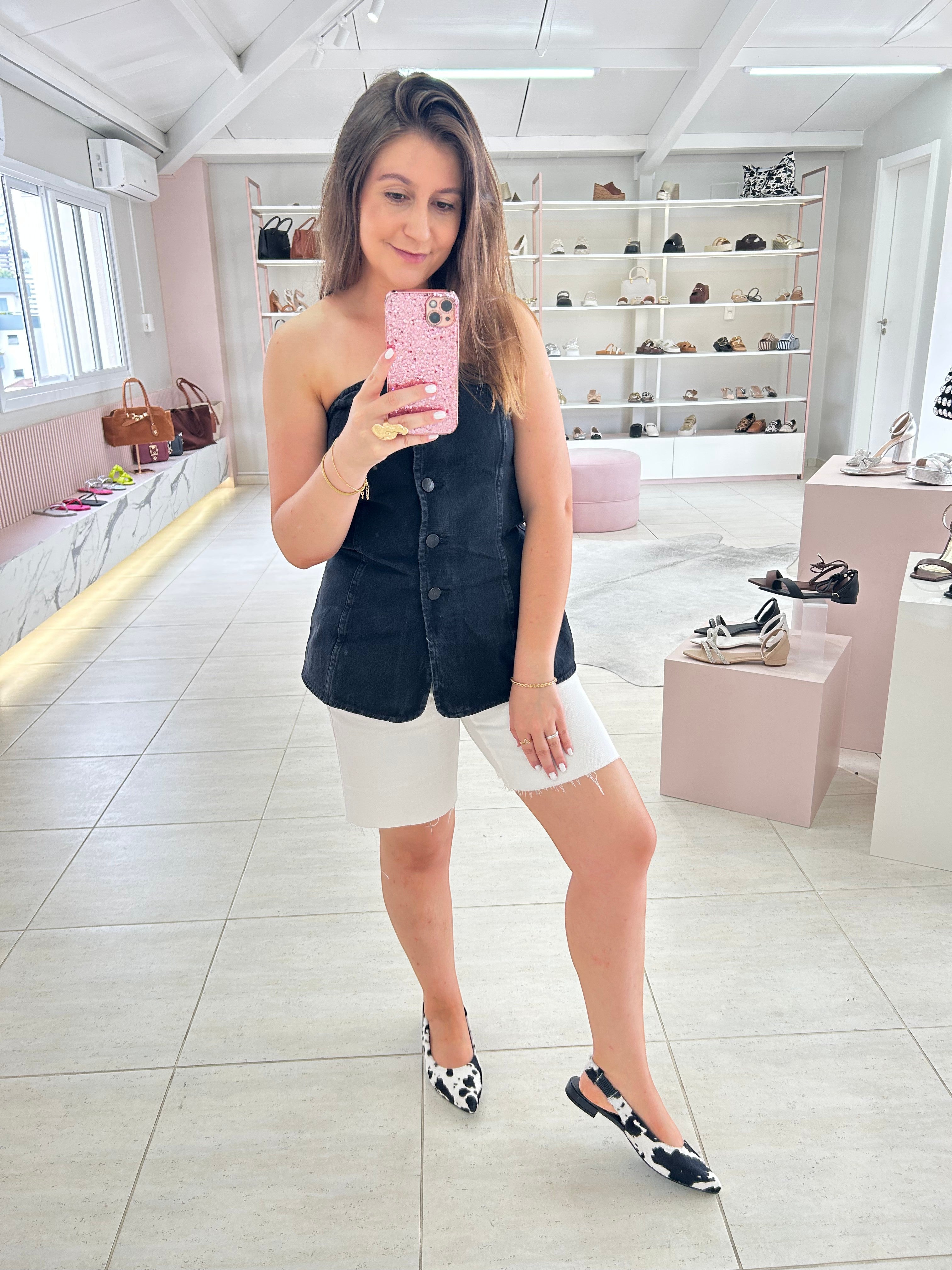 Mulher usando slingback Beyou Shoes de couro com estampa animal print de vaca preta e branca em loja de calçados