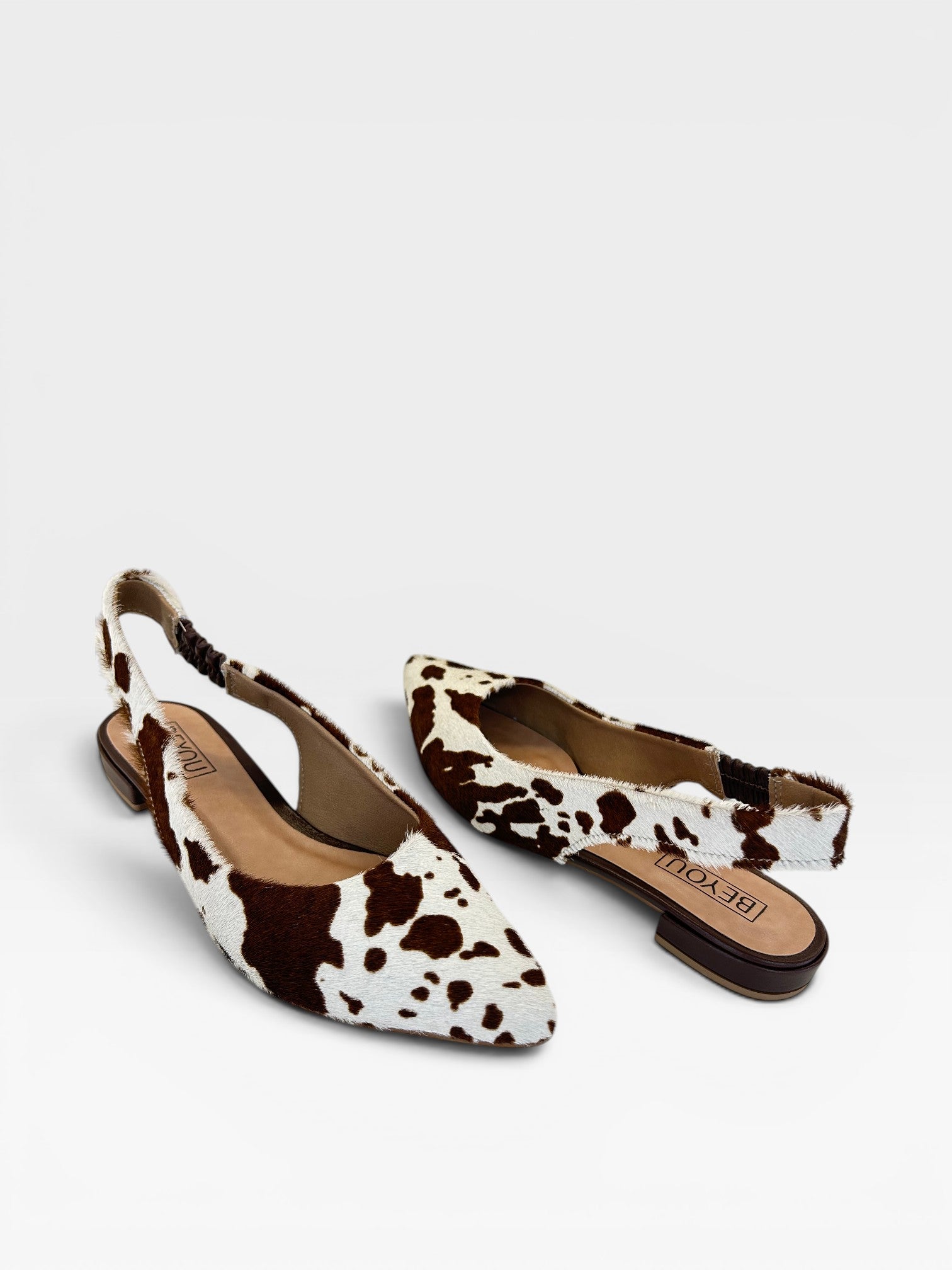 Slingback Beyou Shoes Barretos em couro com estampa animal print de vaca, bico fino e salto baixo.