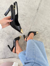 Slingback Beyou Shoes Bristol em couro preto com salto alto e ponteira metálica dourada, calçado no pé com jeans.