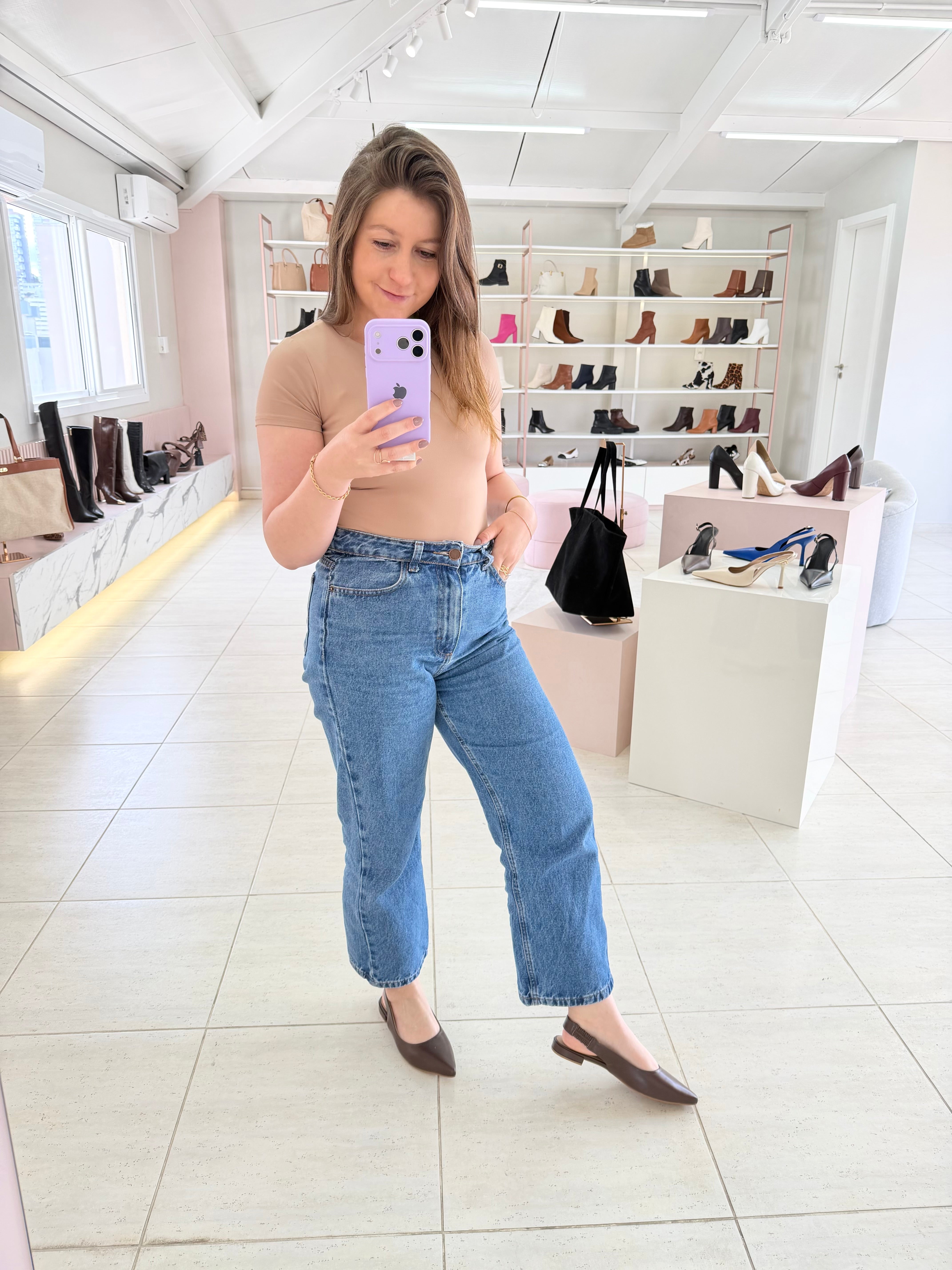 Mulher usando slingback marrom de couro Beyou Shoes em loja com prateleiras de calçados ao fundo