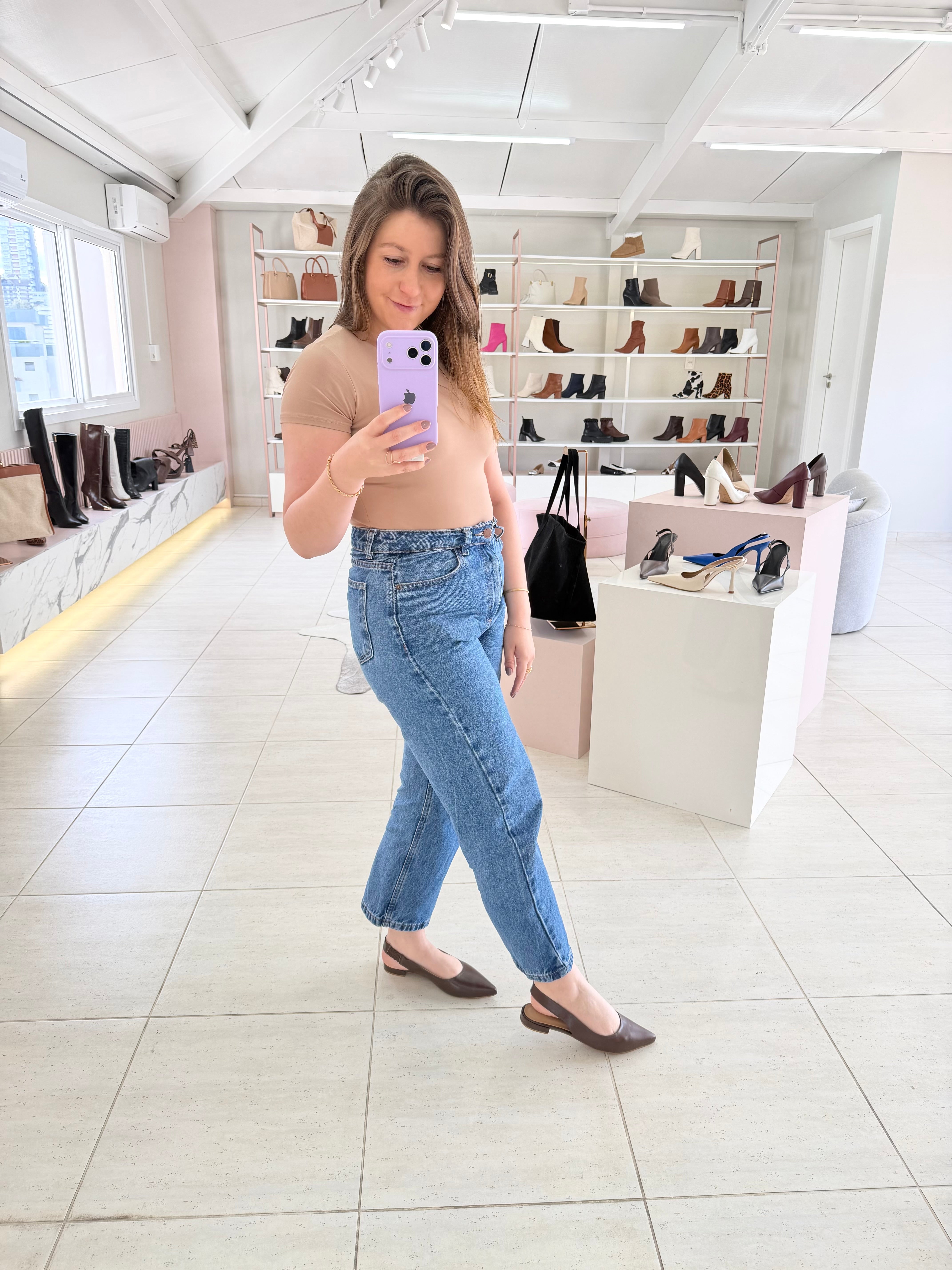 Mulher usando slingback marrom de couro Beyou Shoes com calça jeans e blusa bege em loja de calçados