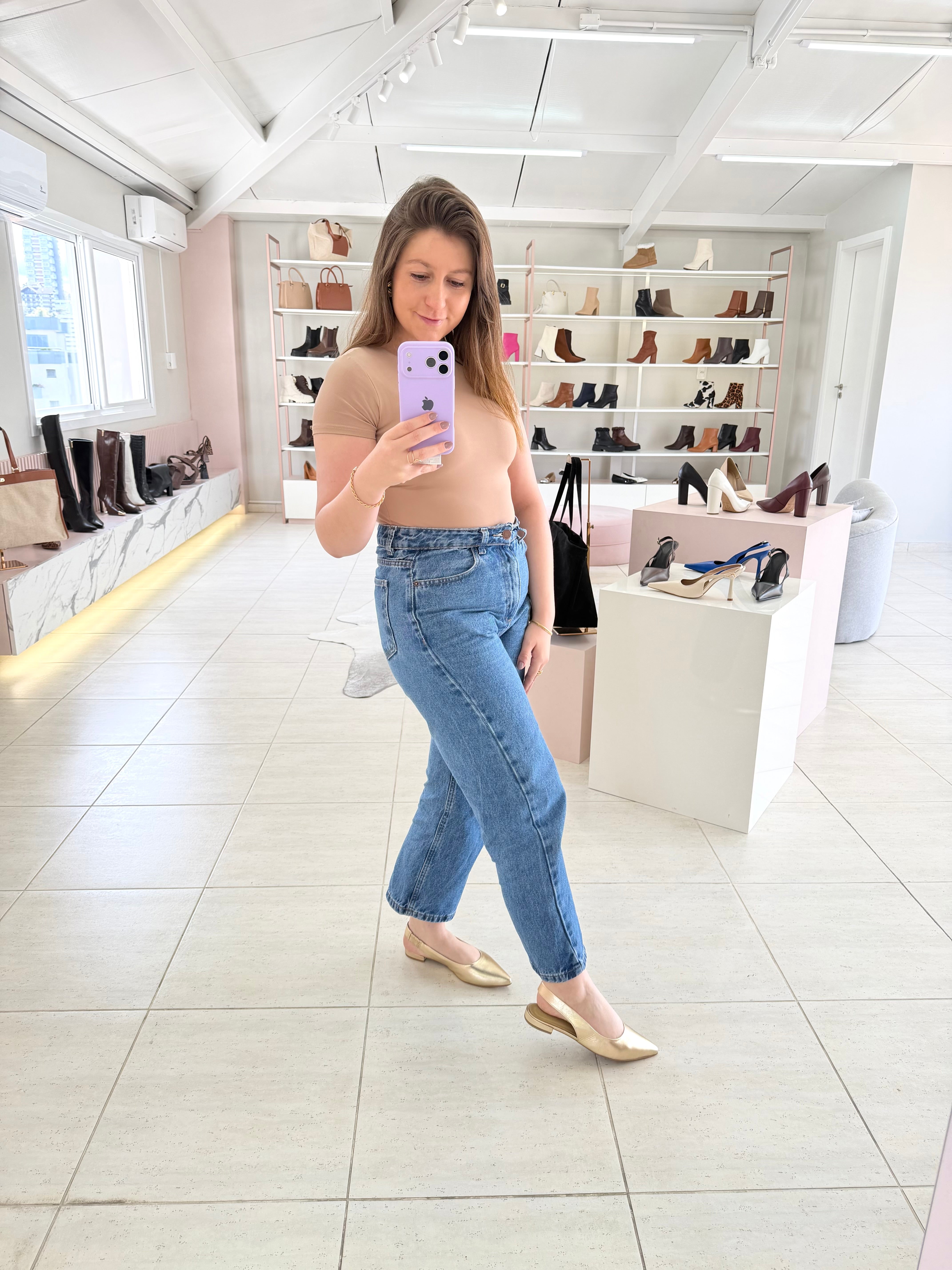 Mulher usando slingback Beyou Shoes ouro light de couro sem salto em loja de calçados com prateleiras ao fundo